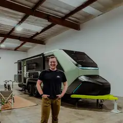 Troy standing beside an Evotrex camper trailer in a showroom